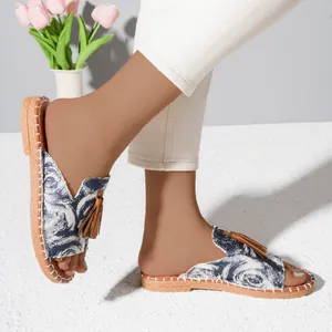 Detailed view of women's flat beach sandals with fringe tassel and blue patterned fabric