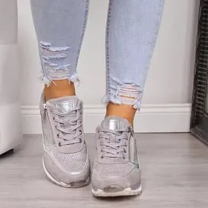 Close-up view of stylish grey wedge sneakers featuring side zipper and rhinestone detail