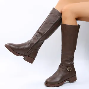 Detail of brown tall knee-high boots with side zipper and buckle on a model.