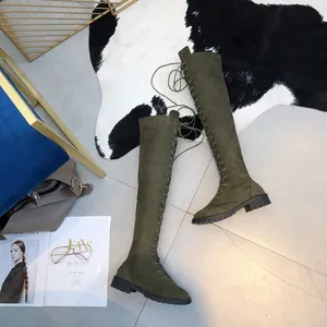 Close-up detail of olive green lace-up over-the-knee boots with sturdy flat soles.