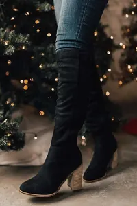 Detail view of black suede knee-high boots with textured wood-grain chunky heels