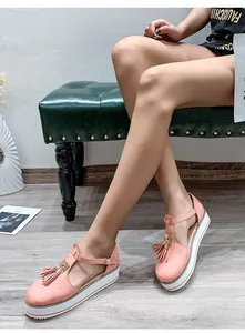 Close-up of pink platform sandals with decorative tassels and a T-strap buckle closure