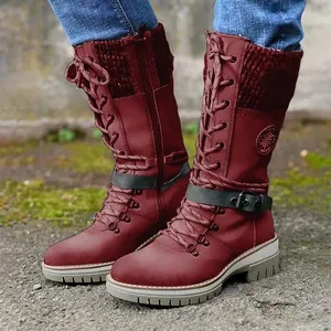 Close-up of burgundy mid-calf boots featuring knitted patchwork and side buckle detail