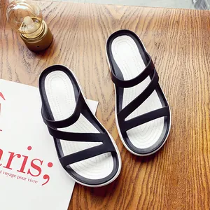 Detailed top view of minimalist black and white flat sandals on a wooden surface