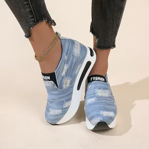 Nahaufnahme von Plateau-Slippern aus Denim mit Used-Look und dicken weißen Sohlen.