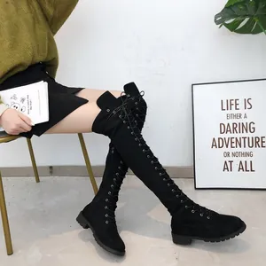 Detailed view of black lace-up over-the-knee boots with flat soles on model