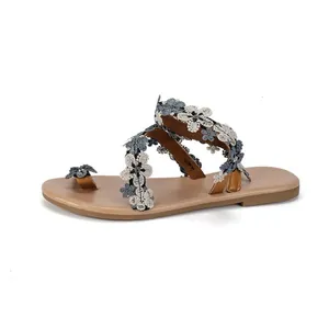 Close-up of bohemian flat sandals decorated with delicate blue and white fabric flowers.
