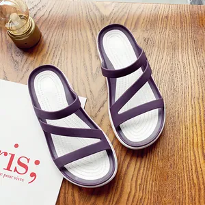Top view of stylish purple and white flat summer sandals on a wooden surface.