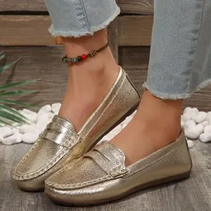 Detail view of metallic gold slip-on loafers for women with a shiny textured finish