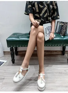 Detailed view of stylish white T-strap platform sandals with tassels worn by a model