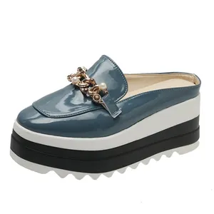 Detail view of blue patent leather platform mules with elegant gold chain and pearl accent.