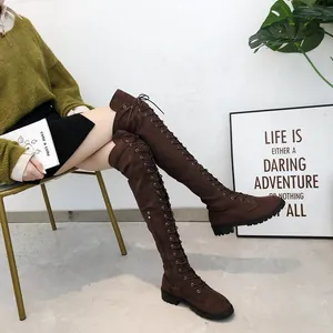 Detailed view of brown lace-up over-the-knee boots on a model sitting down