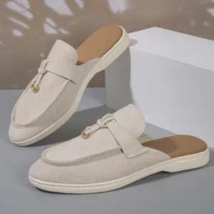 Detailed side view of beige suede mules with decorative strap and gold buckle detail.