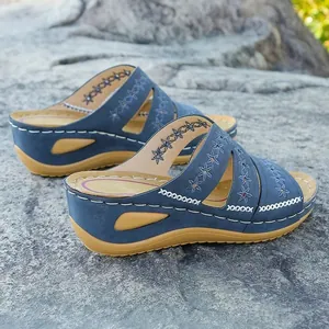 Détail de sandales à talons compensés brodées bleues avec motifs floraux.