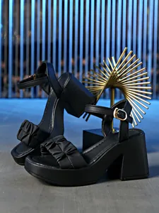 Detailed view of stylish black platform sandals with elegant ruffled straps and gold buckle