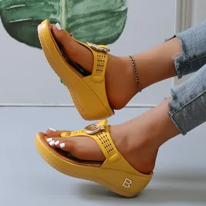Primer plano de chanclas con cuña amarillas para mujer con hebilla metálica y suela gruesa moderna