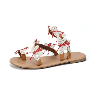 Detailed view of white and red embroidered butterflies on Bohemian flat sandals
