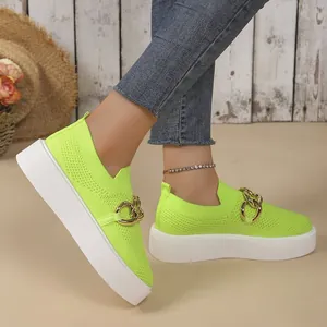 Side view of neon green fly-knit platform sneakers with decorative gold chain detail.