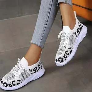 Detailed view of women's white knit sneakers with leopard print pattern worn with denim jeans