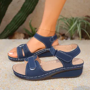 Primo piano di sandali con zeppa retrò blu con cinturini a strappo regolabili sulla sabbia