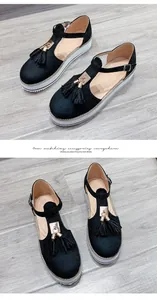 Detailed view of black suede platform sandals with tassel accents and T-straps.