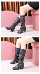 Detailed view of black slouchy high boots with belt buckle straps and chunky heels