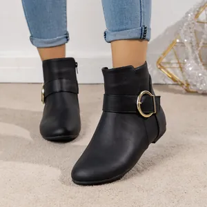 Detailed view of black fashion ankle boots with a decorative gold buckle and side zipper.