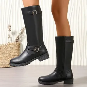 Close-up detail of black equestrian tall boots featuring buckle straps and a low heel design