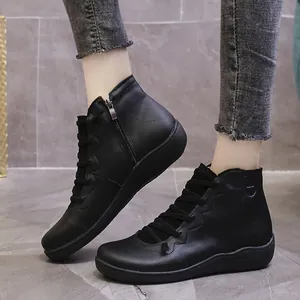 Detailed macro view of black leather casual ankle boots featuring side zipper and lace-up accents