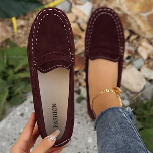 Detailed view of burgundy suede loafers featuring white contrast stitching and round toe.