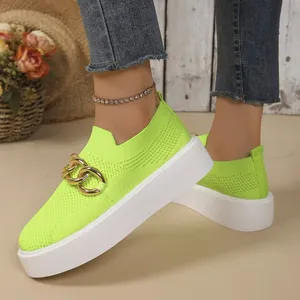 Detail of fluorescent green knit sneaker featuring a gold chain and white platform sole