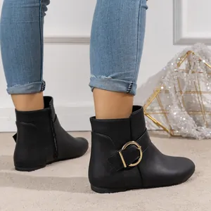 Close-up of black flat ankle boots with gold buckle and side zipper for a stylish look.