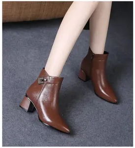 Detail shot of brown pointed-toe ankle boots with thick heels and metal buckle