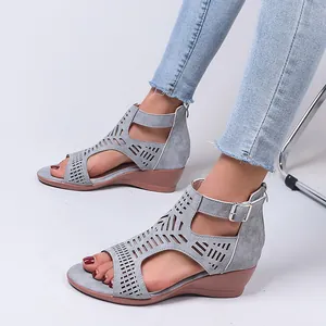 Close-up of grey cut-out wedge sandals with adjustable ankle strap and buckle detail.