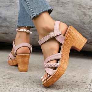 Close-up of pink chunky heel platform sandals with braided straps and gold buckle.