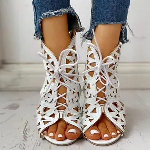 Gedetailleerd vooraanzicht van witte holle vetersandalen met sleehak voor dames