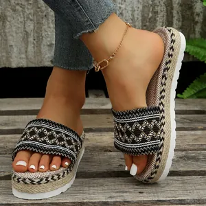Close-up of ethnic patterned strap and straw-woven platform on women's slides.