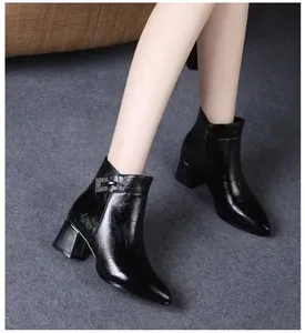 Close-up view of black pointed-toe chunky heel ankle boots with elegant crocodile texture