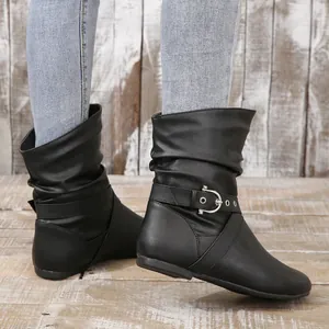Detail view of women's black flat slouch boots featuring metal buckle strap and side zipper