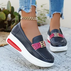 Detail view of casual dark blue platform loafers with red accents and a gold buckle.