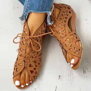 Close-up of fashionable brown cutout lace-up wedge sandals worn on feet with white nails