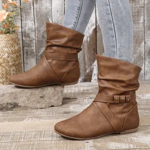 Fashionable brown slouchy flat ankle boots featuring decorative buckle straps and rivets.