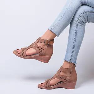Detail of women's brown wedge sandals with cutout design and ankle buckle strap.
