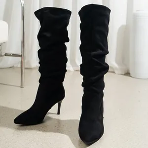 Detailed shot of black slouchy high boots with a pointed toe and stiletto heel