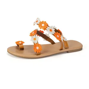 Close-up detail of bohemian flat sandals with orange and white embroidered daisy flowers