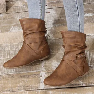Close-up detail of brown slouchy ankle boots with cross straps and metal studs.