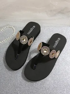 Exquisite close-up of rhinestone and pearl circular decorations on black platform flip flops
