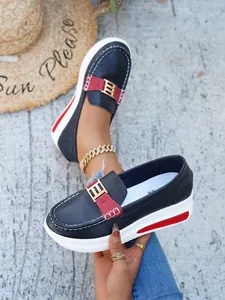 Detail view of navy blue platform loafers with gold buckle and stylish red accents
