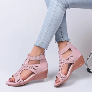Elegant pink laser-cut wedge sandals with buckle strap shown on feet in a studio setting