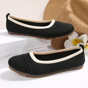Detail view of black knitted ballet flats featuring beige rim and flexible rubber sole